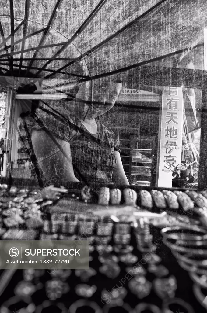 a female vendor smiles behind a screen where jewelry is displayed, ruili yunnan china
