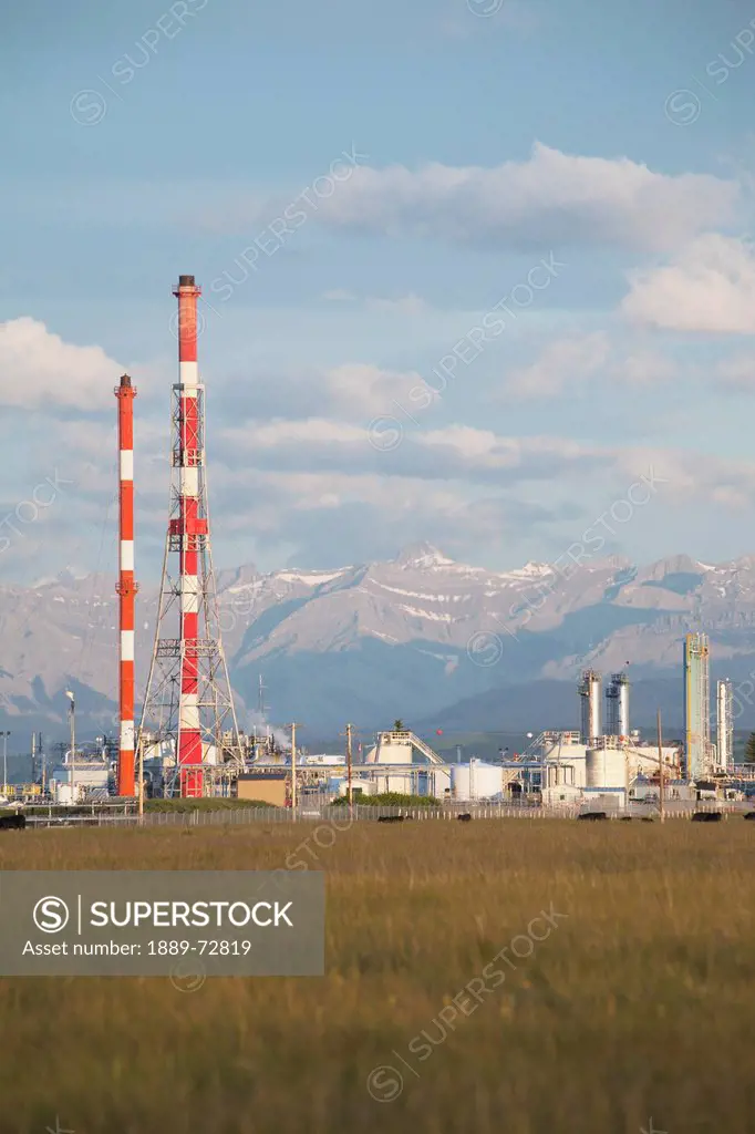 gas plant with red and white towers and mountains in the background, cochrane alberta canada