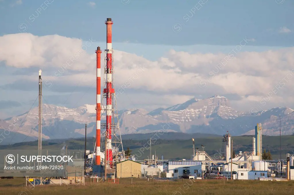 gas plant with red and white towers and mountains in the background, cochrane alberta canada