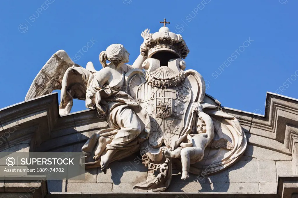 A royal shield on the alcala gate supported by fame with the aid of a child, madrid spain