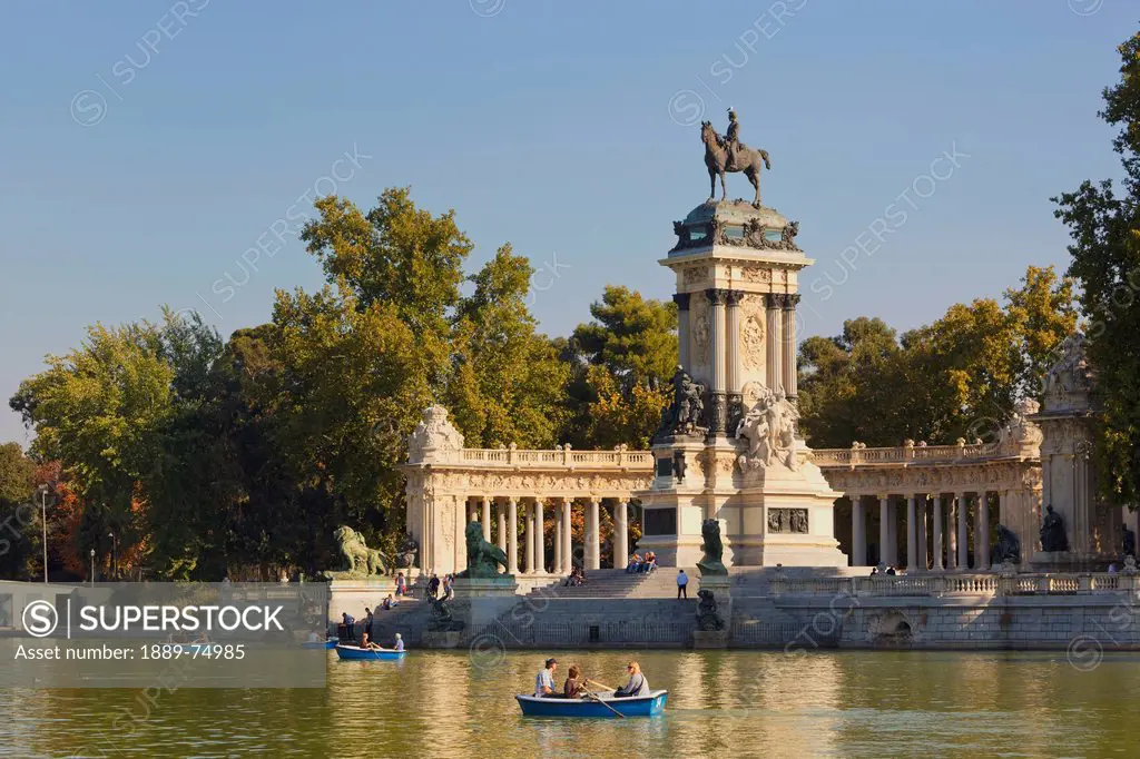 Rowing on the lake in el retiro gardens with the monument to king alfonso xii in background, madrid spain