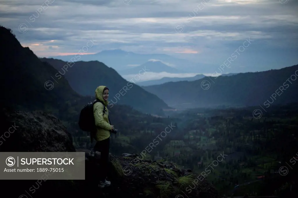 Woman overlooking a valley with volcanos in the background early in the morning, cemoro lawan java indonesia