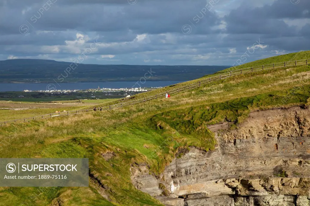 People walking along the grass at the cliffs of moher, county clare ireland