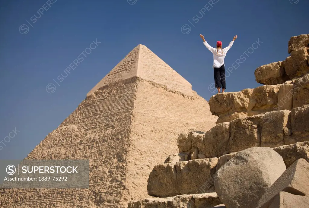 A Woman Tourist Raises Her Arms In Front Of The Pyramids Of Giza Near Cairo, Giza Egypt