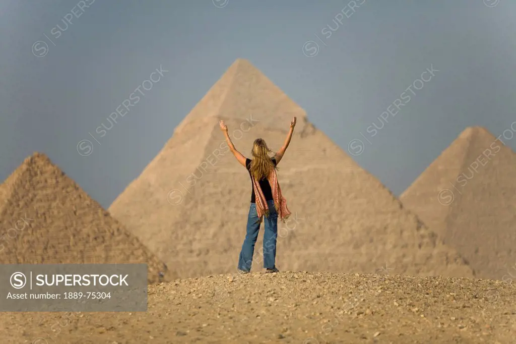 A Female Tourist Raises Her Arms And Looks Out Toward The Pyramids Of Giza Near Cairo, Giza Egypt