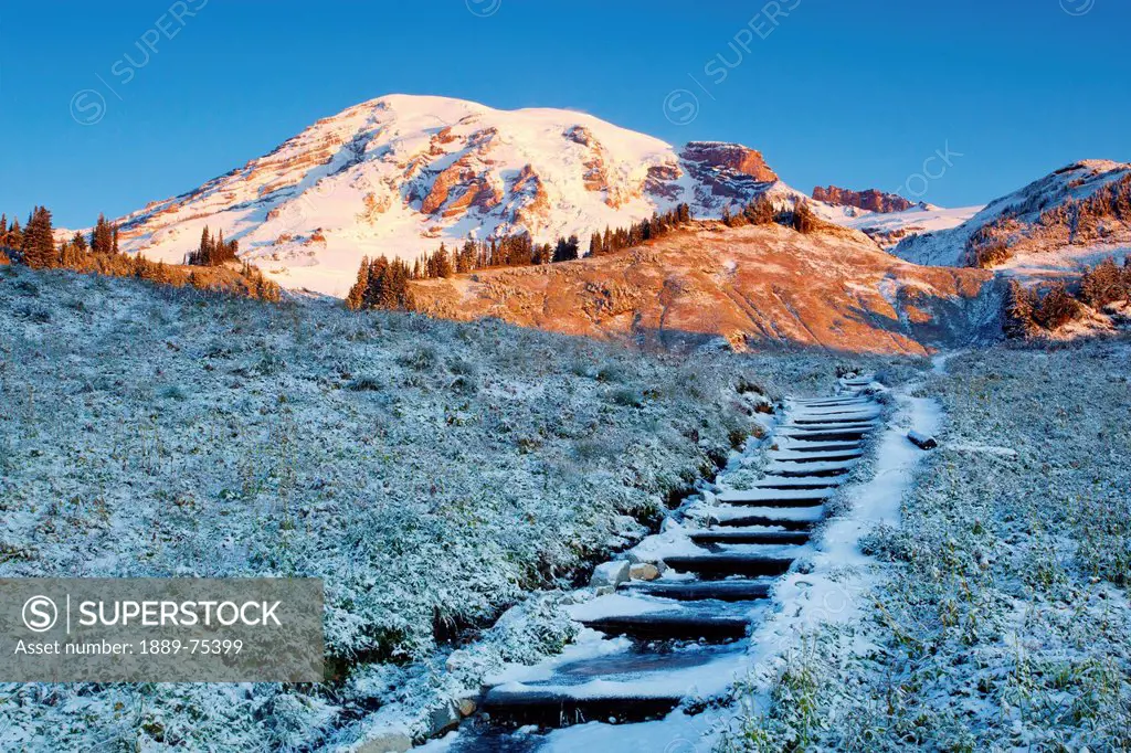Sunrise Over Mount Rainier And First Autumn Snow Covering Steps Leading Up A Hill, Washington United States Of America