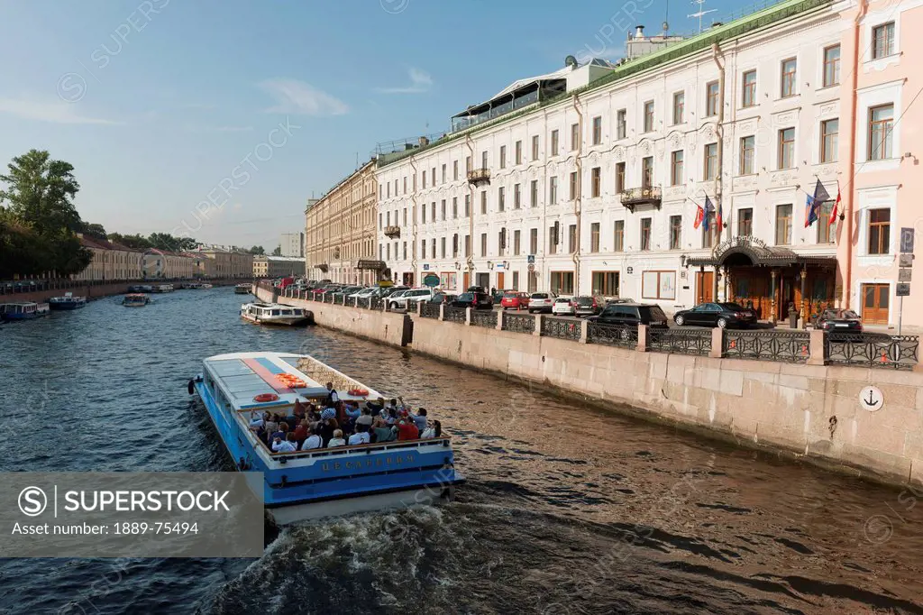 A boat carrying passengers travels down moyka river, st. petersburg russia