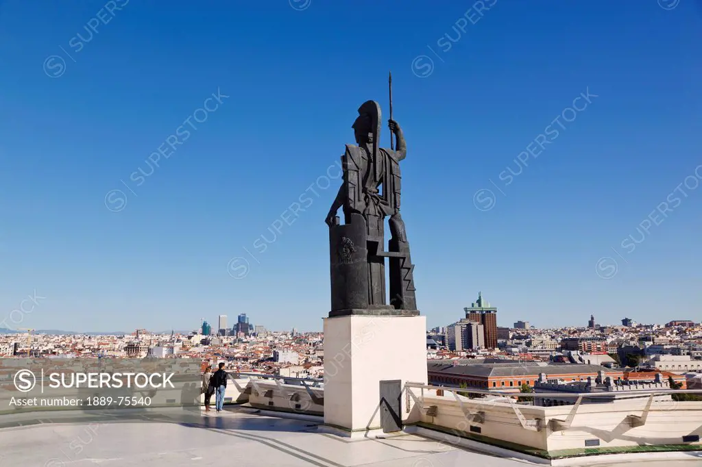 Couple admiring the view beside the athena statue on the terrace of the circulo de bellas artes, madrid spain