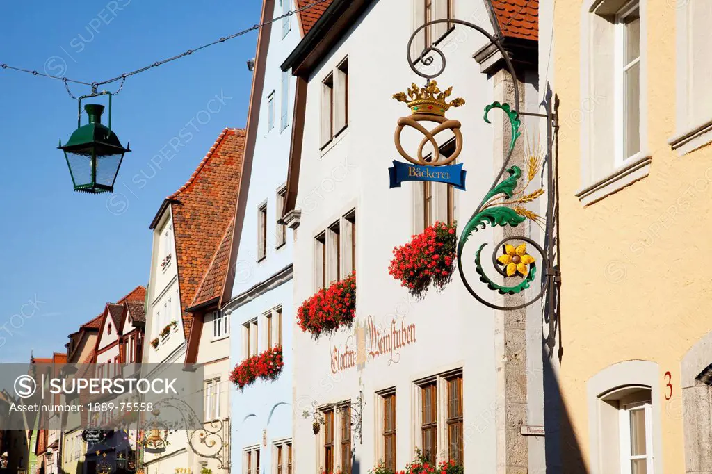 Hanging sign and lantern with blossoming flowers in window planter boxes, rothenburg ob der tauber bavaria germany
