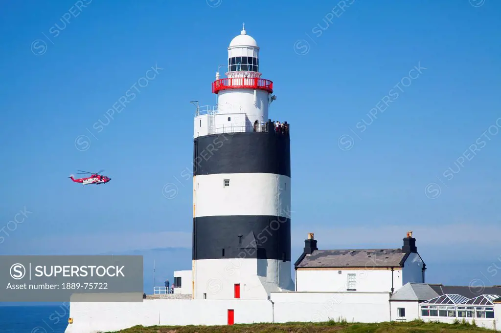 A helicopter flies by hook lighthouse, county wexford ireland