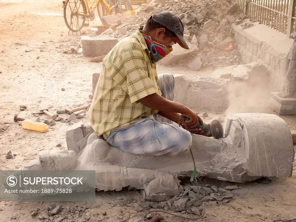 A man carves a statue out of stone with a hand held saw, mahabalipuram tamil nadu india