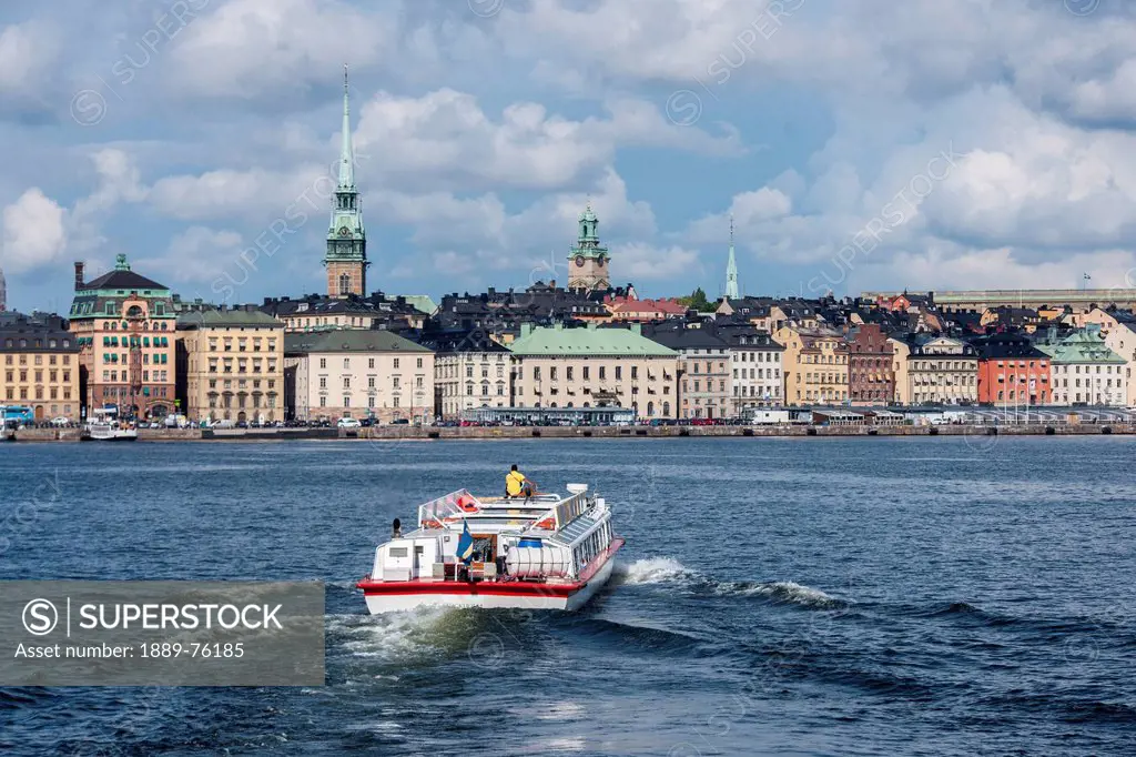 A boat traveling through the water and buildings along the water´s edge, stockholm sweden