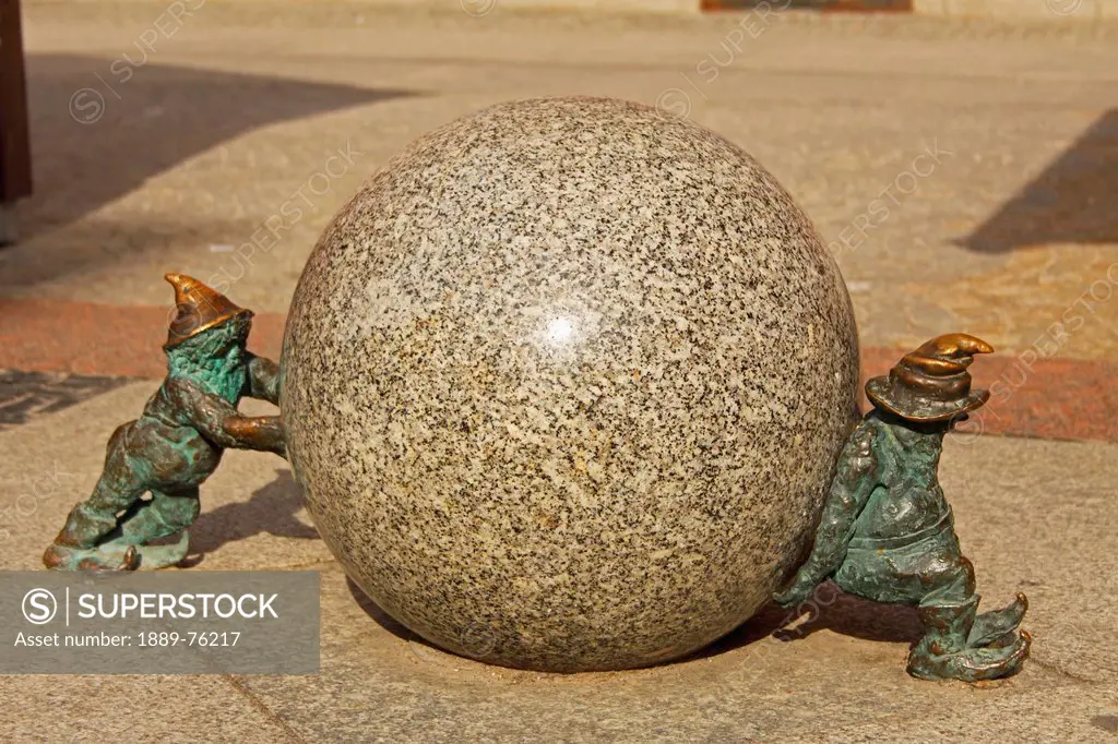 Bronze sculptures of two gnomes pushing a boulder, wroclaw poland