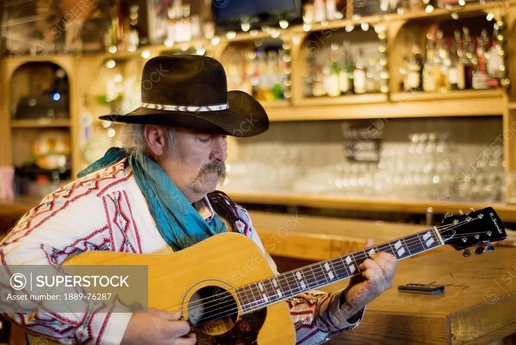 Cowboy playing guitar in a saloon, bragg creek alberta canada