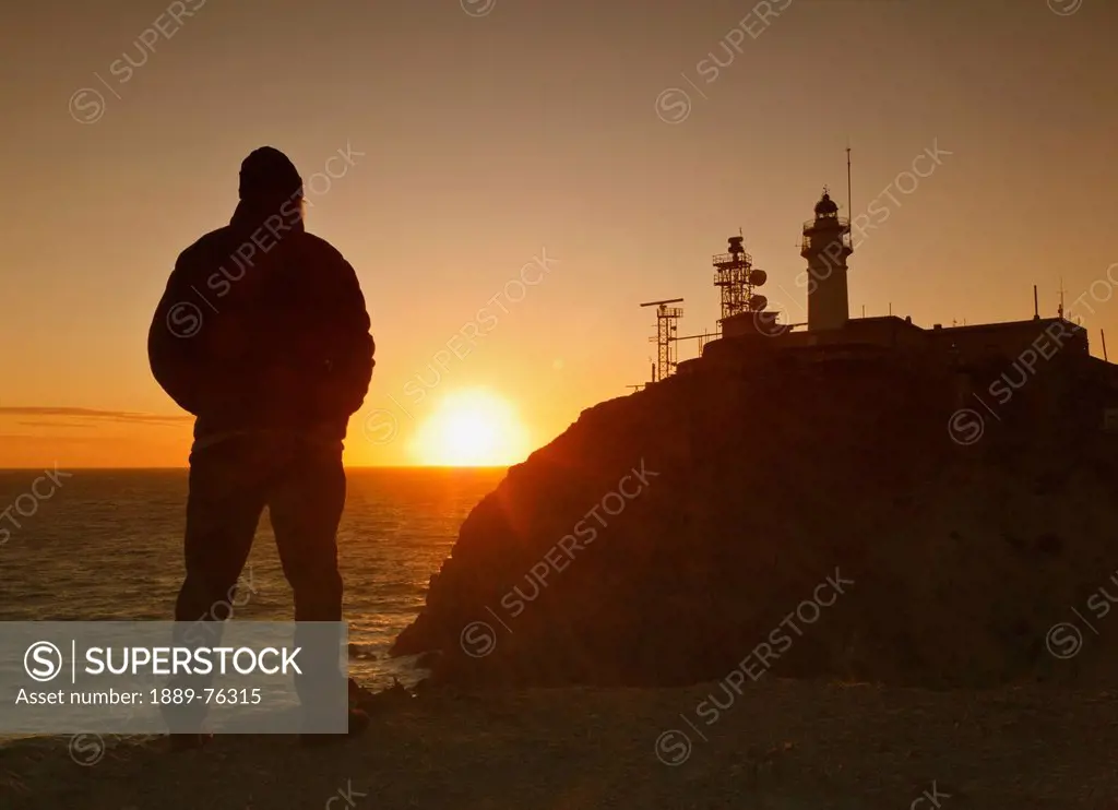 Silhouette of a person standing and looking at the lighthouse and communications apparatus on the headland cabo de gata_nijar natural park, cabo de ga...