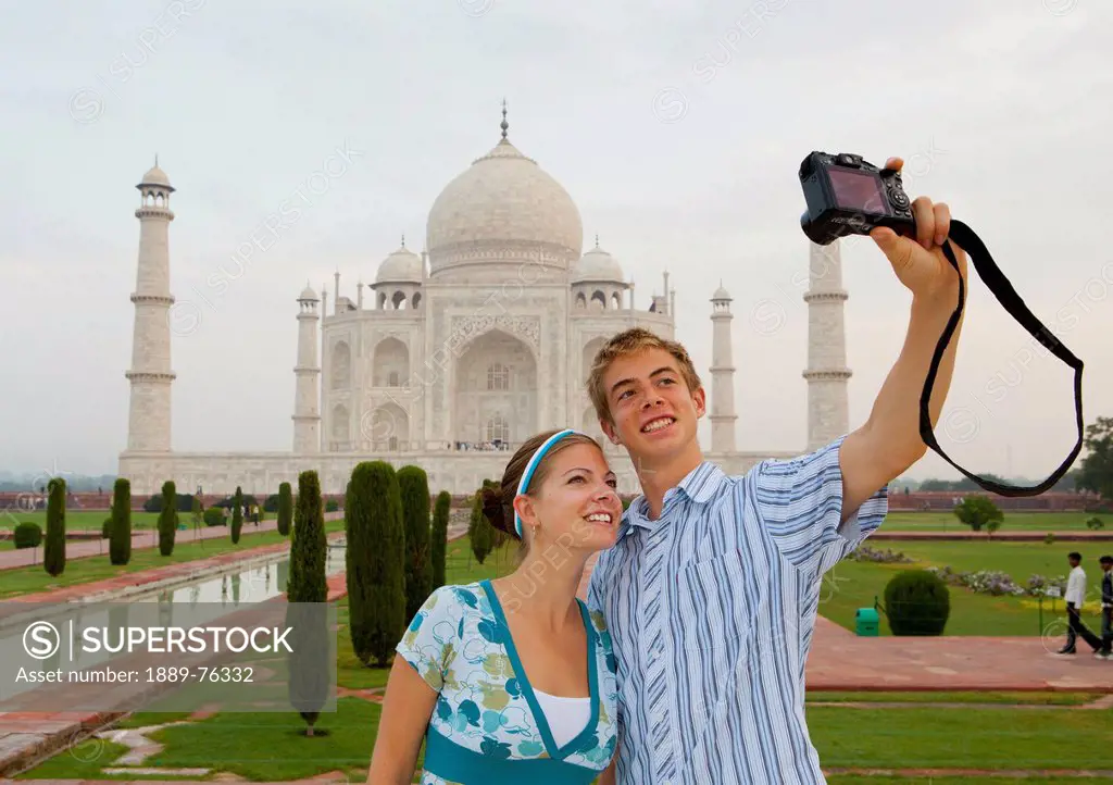 A young man and woman photograph themselves with the taj mahal in the background, agra uttar pradesh india