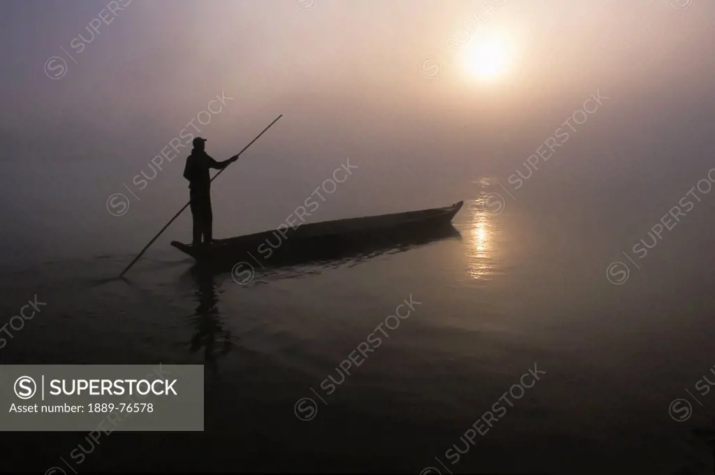 A Man Pushes His Dugout Canoe Along The Rapti River Near Sauraha And Chitwan National Park At Dawn, Nepal