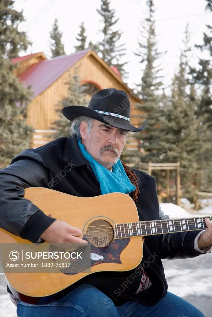 Cowboy playing guitar outdoors in winter, bragg creek alberta canada