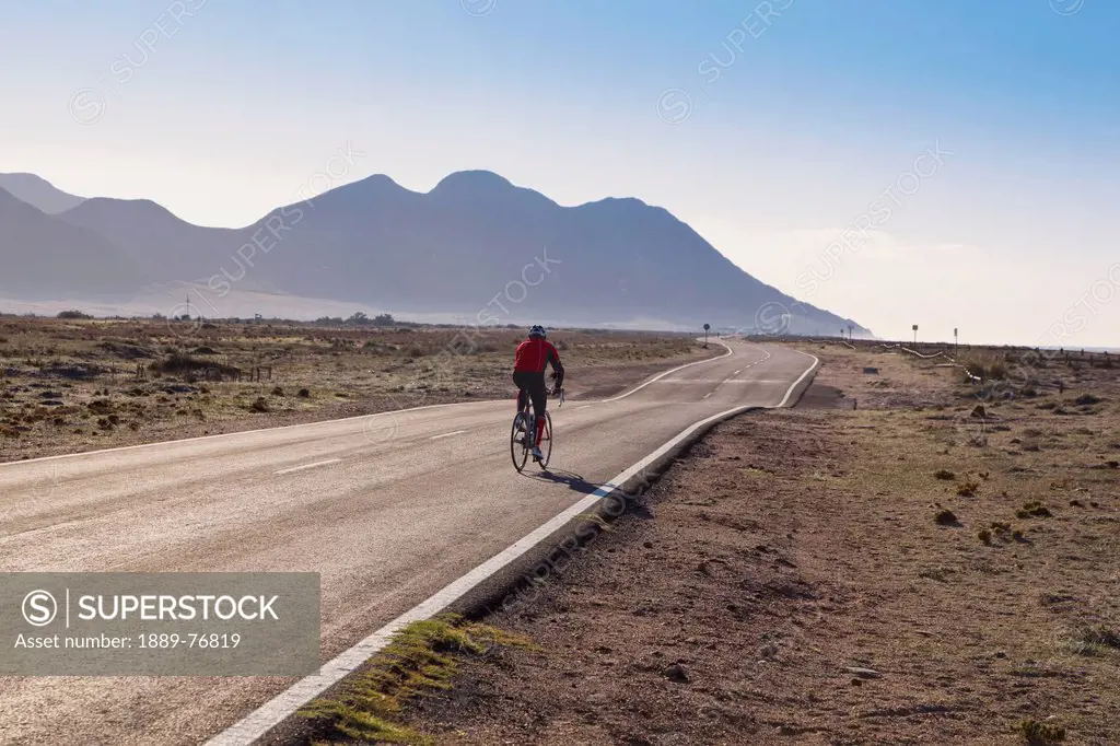 Bike rider on road between cabo de gata town and almadraba de monteleva, almeria province spain