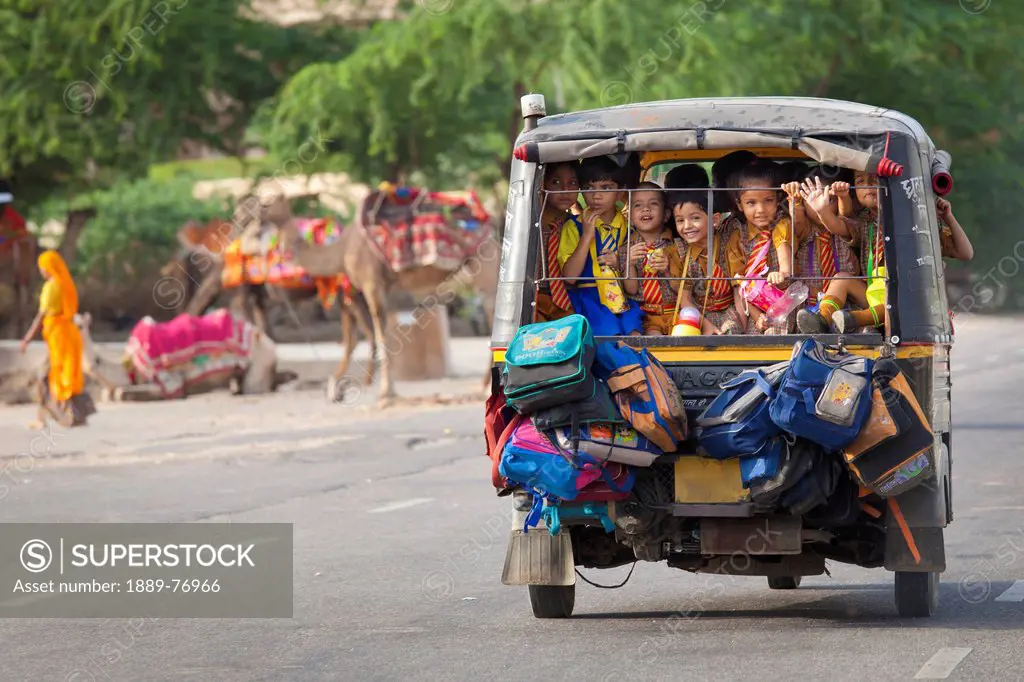 Children riding in a small bus with their bags attached to the back, jaipur rajasthan india