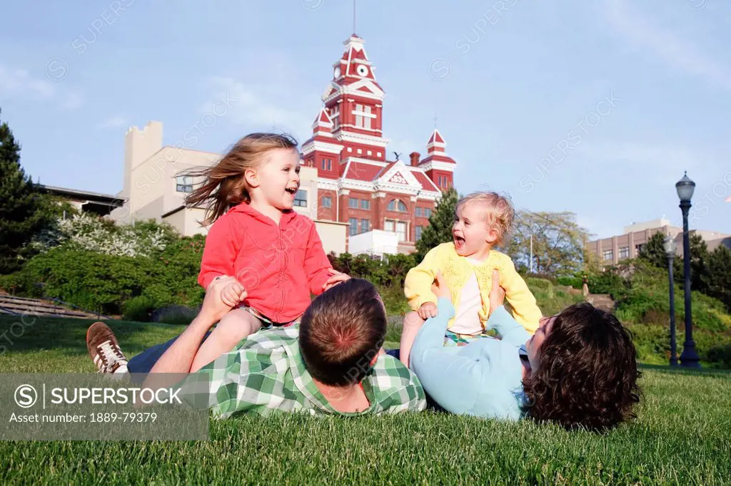 two daughters play with parents in grass, bellingham washington united states of america