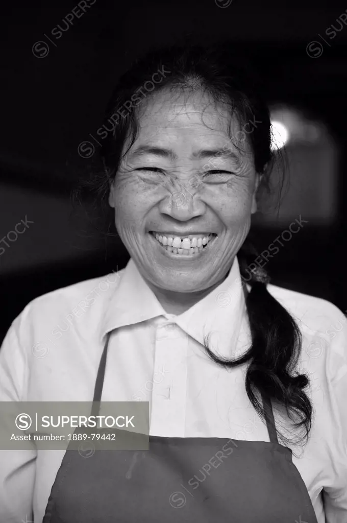 a woman wearing an apron with a big smile, ruili yunnan china