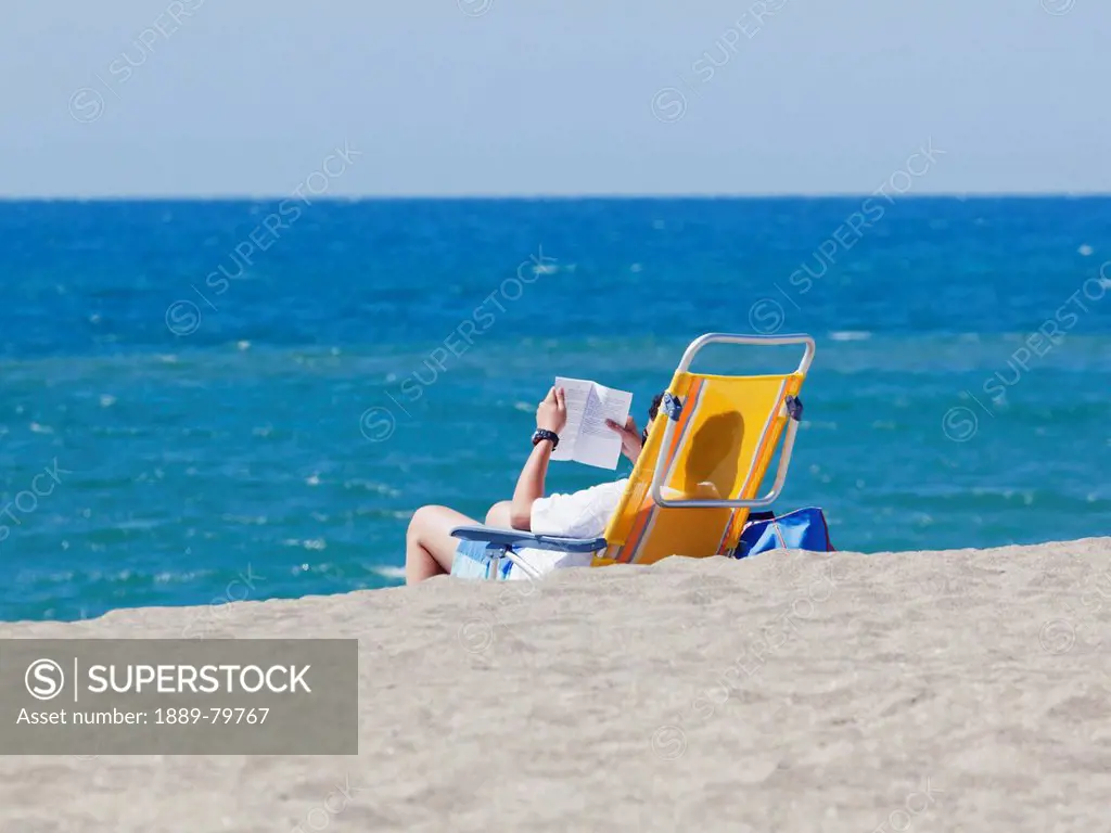 Tourist Reading On A Chair On The Beach On Cala De Mijas, Fuengirola Malaga Province Costa Del Sol Spain