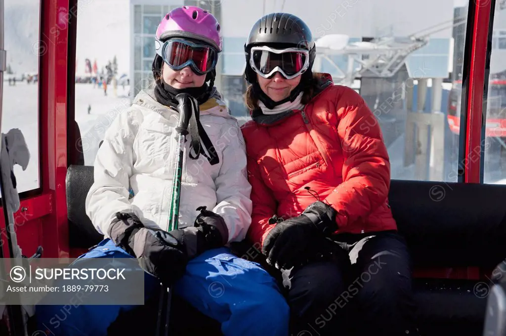 two skiers riding a gondola lift at a ski resort, whistler british columbia canada