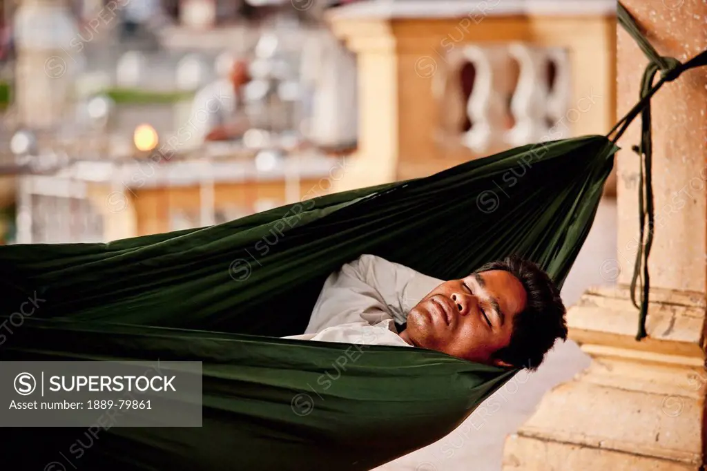 A Man Sleeps In A Hammock In The Public Square, Phnom Penh Cambodia