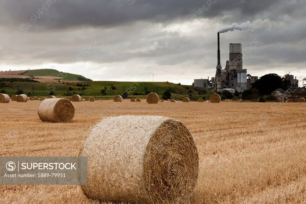 a cement production plant with hay bales in a field in the foreground, lothian scotland