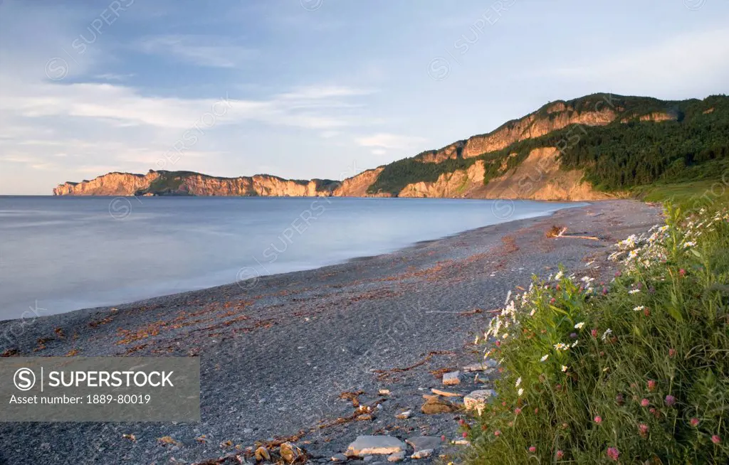 sunrise on a beach and cliffs along the water, quebec canada