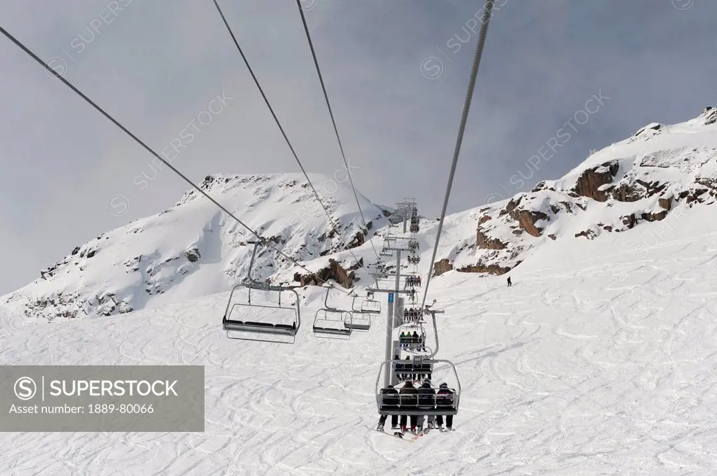skiers riding a chairlift at a ski resort, whistler british columbia canada