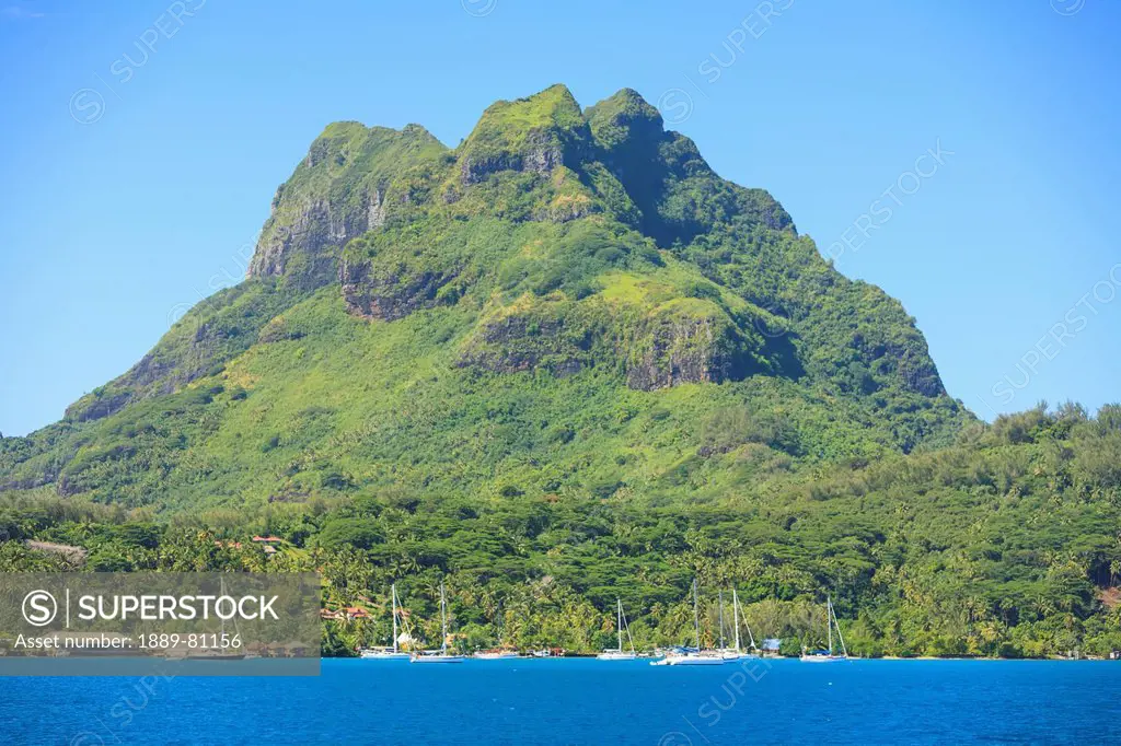 A large rock formation against a blue sky along the coast, bora bora society islands french polynesia south pacific