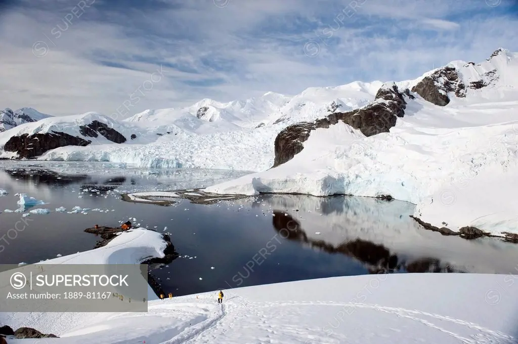 Tourists in yellow jackets explore the coastline, antarctica