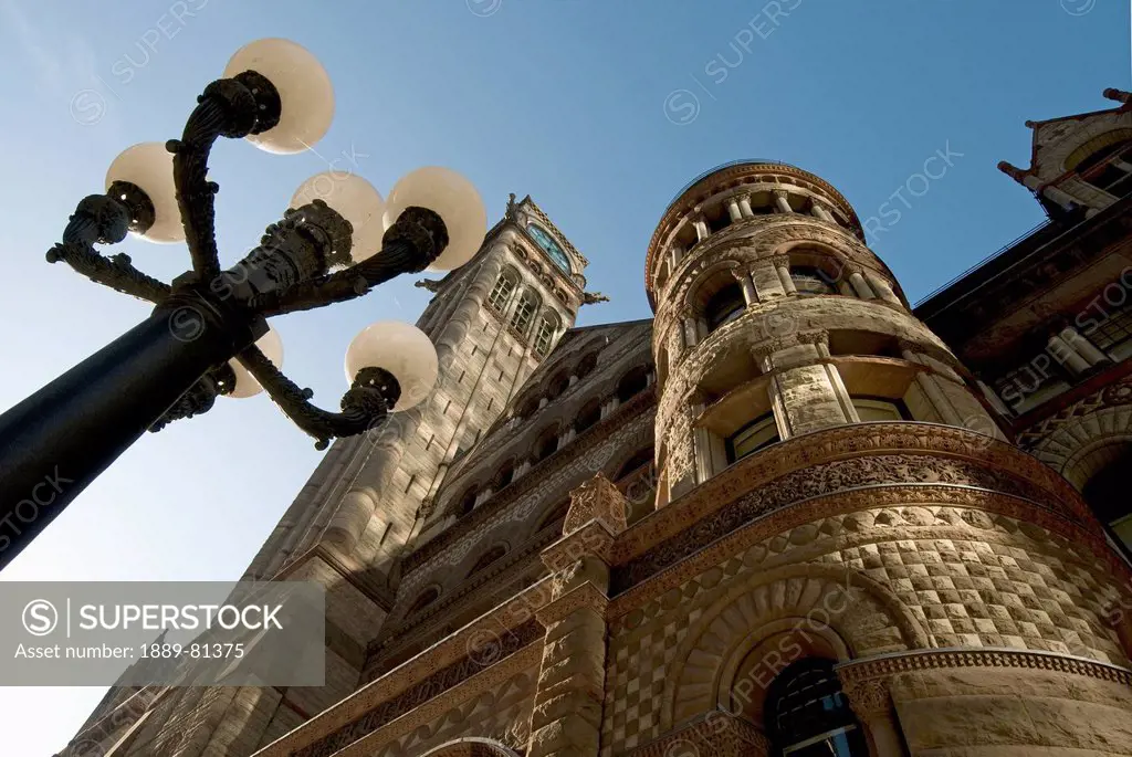 Low angle view of a light post and a building with a clock tower and a round tower, toronto ontario canada