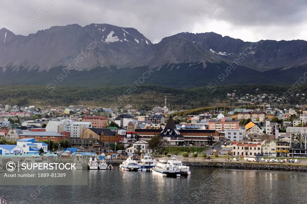Boats in the water at the waterfront of a city with mountains in the background, ushuaia argentina