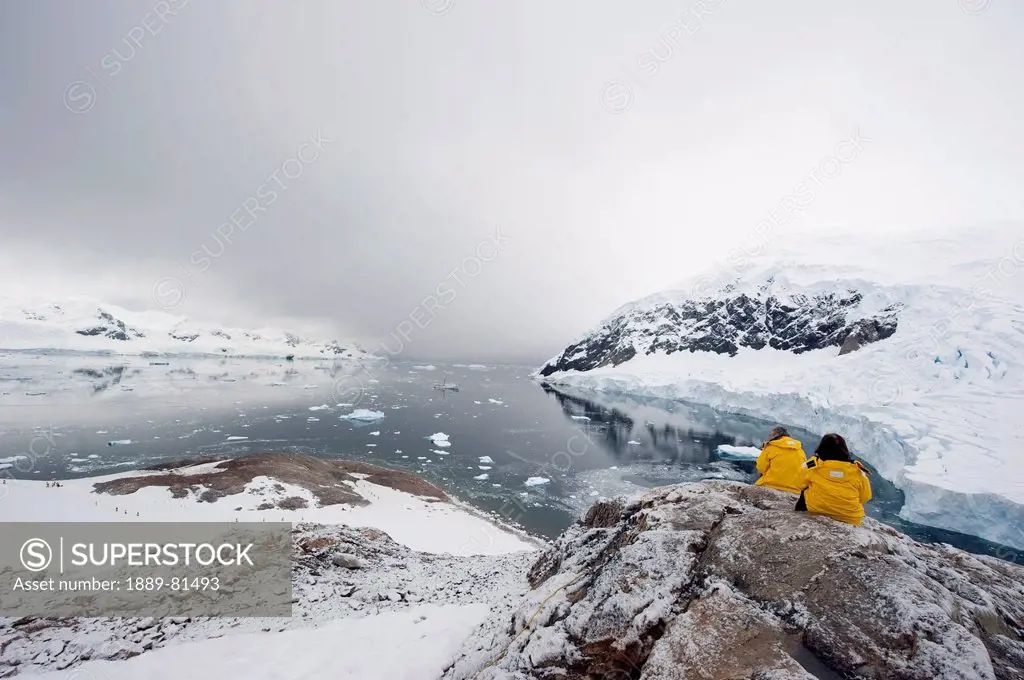 Tourists in yellow jackets by a glacier, antarctica