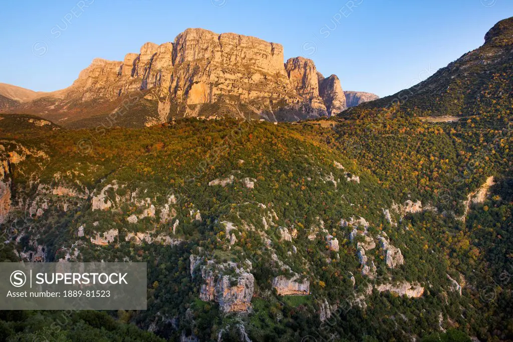 The setting sun lights up the astraka or papigo papingo towers with the village of vikos perching on top of the ridge below,