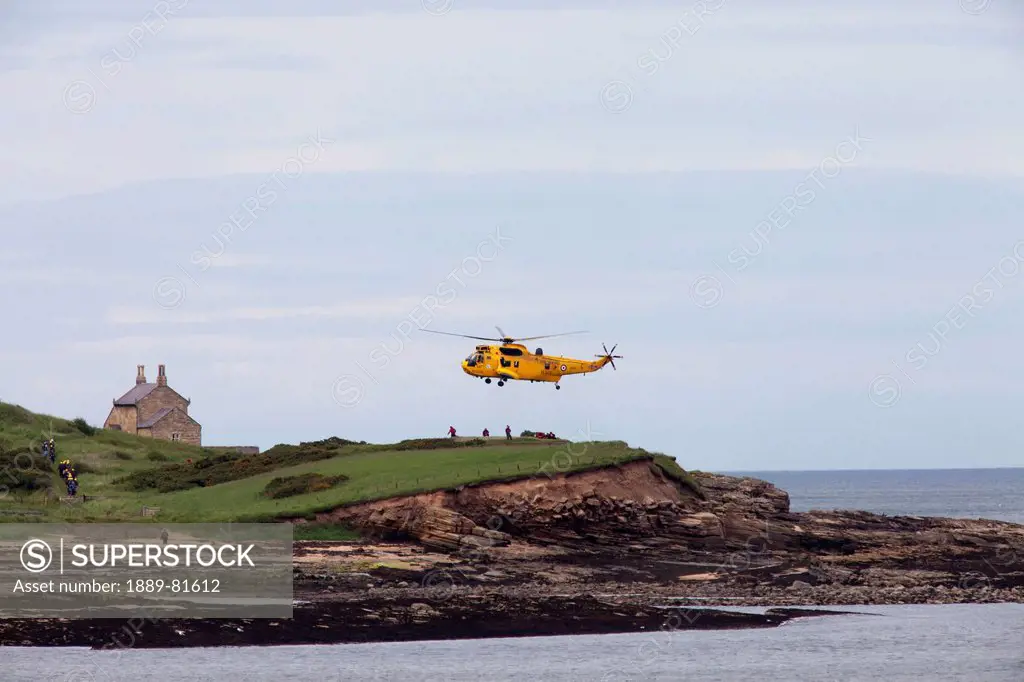 A rescue helicopter taking off from land on the water´s edge, northumberland england