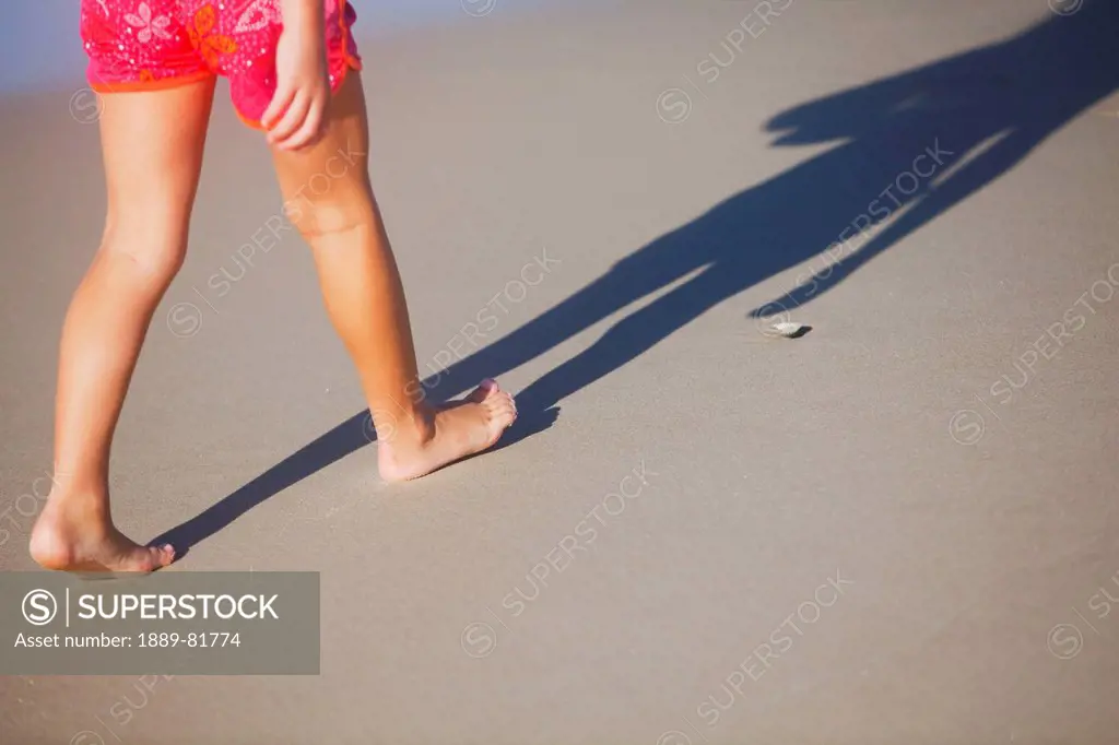 A woman walking in bare feet on the sand, gold coast queensland australia