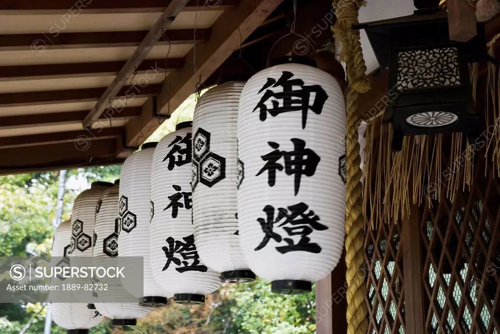 White japanese paper lanterns under the roof of a shrine, kyoto, japan
