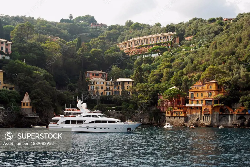 A Yacht Mooring In The Water With Residential Buildings Along The Water´s Edge, Italy