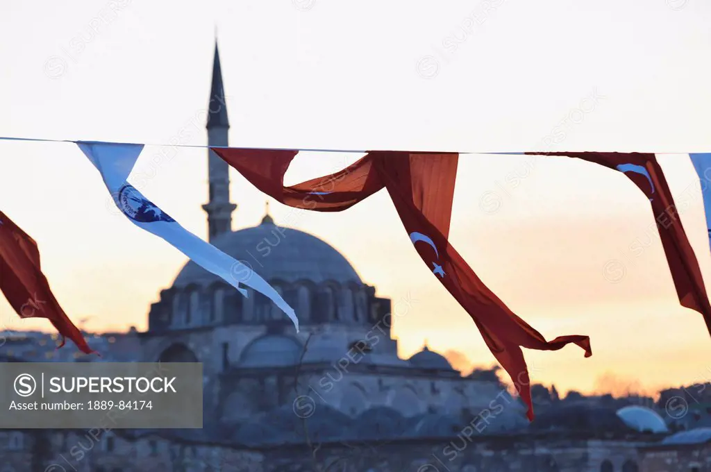 Red And White Fabric Flags Flying With The Rustem Pasha Mosque In The Background At Sunset, Istanbul Turkey