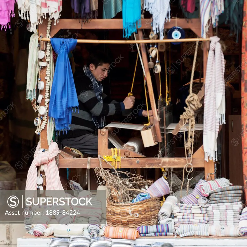 A Young Man Works A Loom In A Shop With Displays Of Fabric Out Front, Istanbul Turkey
