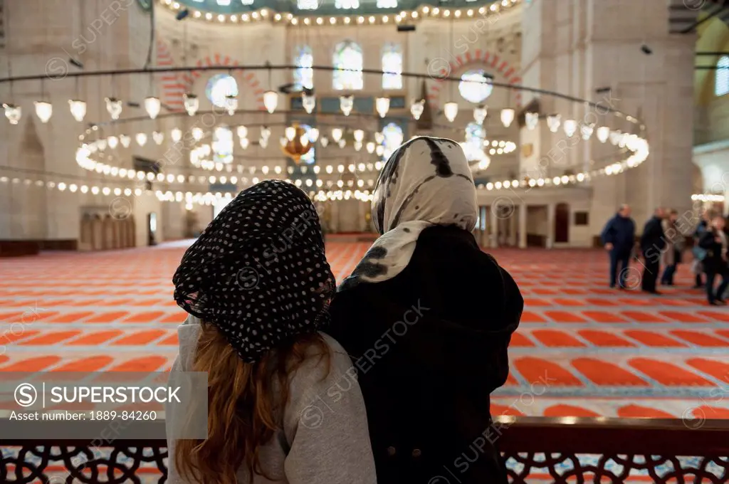 Two Women Looking At The Hanging Light Fixture In The Suleymaniye Mosque, Istanbul Turkey