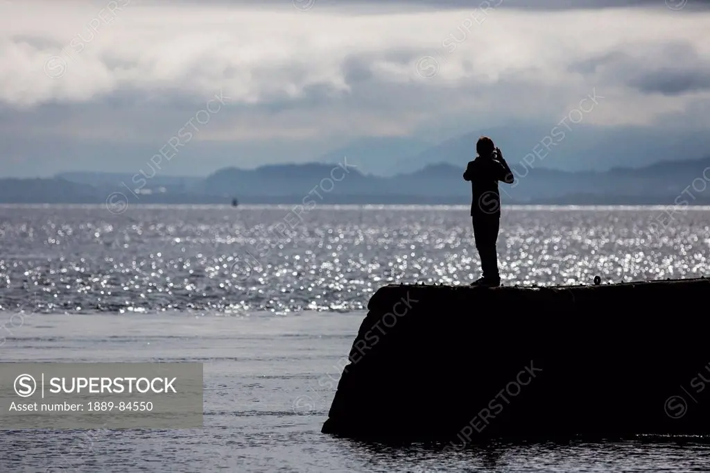 Silhouette Of A Person Taking A Picture Of The Coastline, Moray Firth Scotland