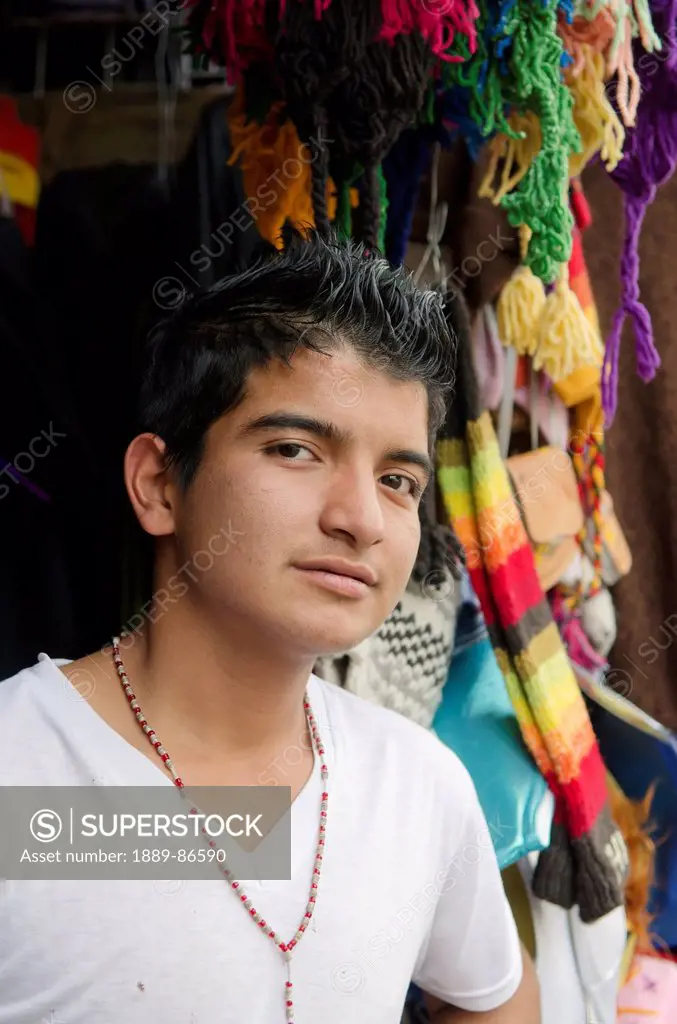 Mexico, Guanajuato State, Portrait Of Boy Standing In Front Of Colorful Scarves And Hats; Guanajuato