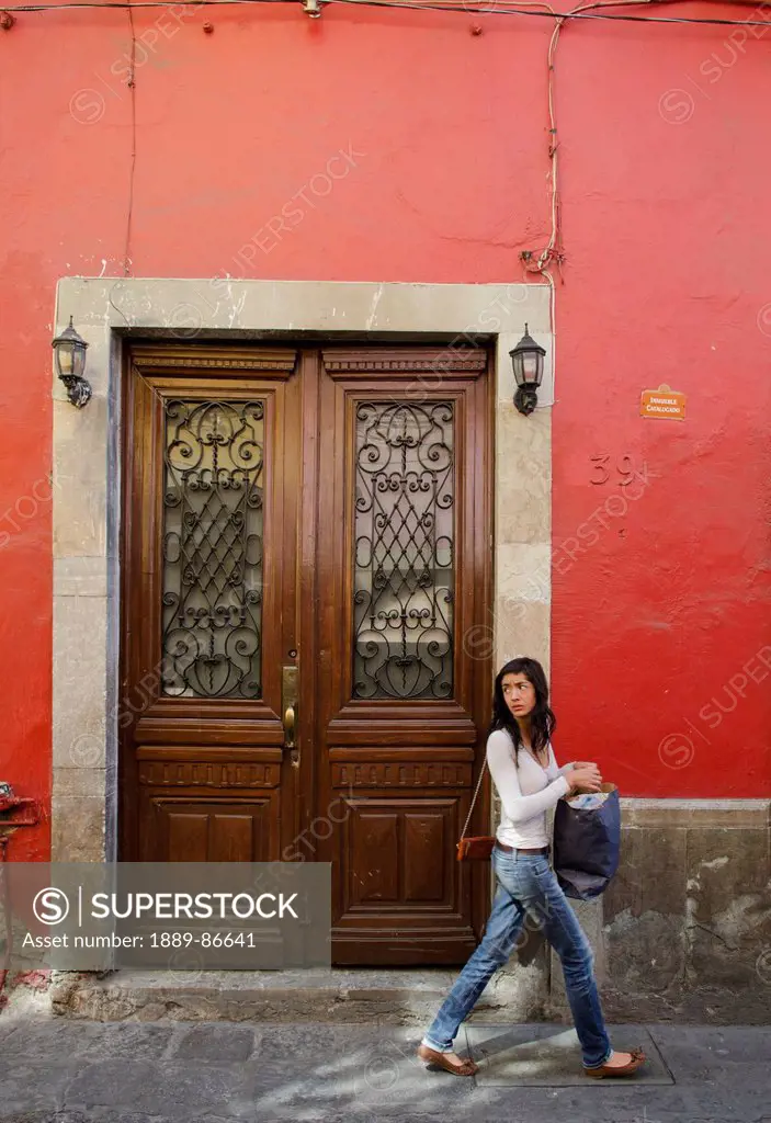 Mexico, Guanajuato, Woman Walking By Old Door; Guanajuato