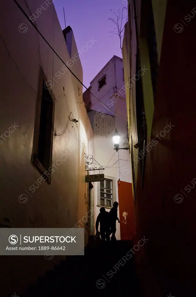 Mexico, Guanajuato, Silhouettes Of People Walking Up Narrow Alley At Night; Guanajuato