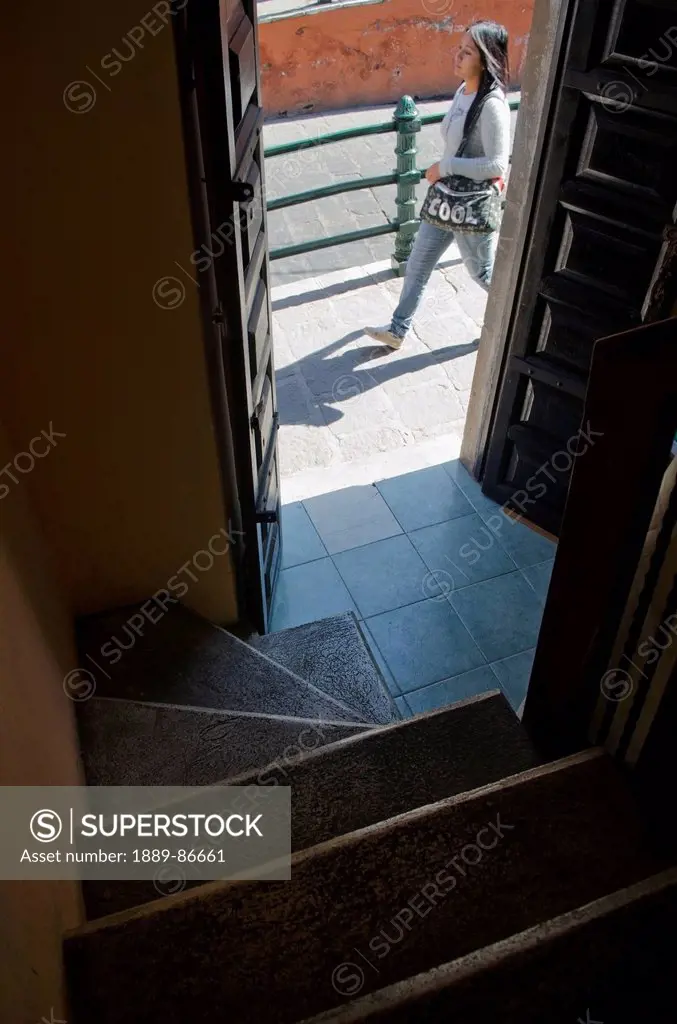 Mexico, Guanajuato, Woman Walking By Open Door To Staircase; Guanajuato